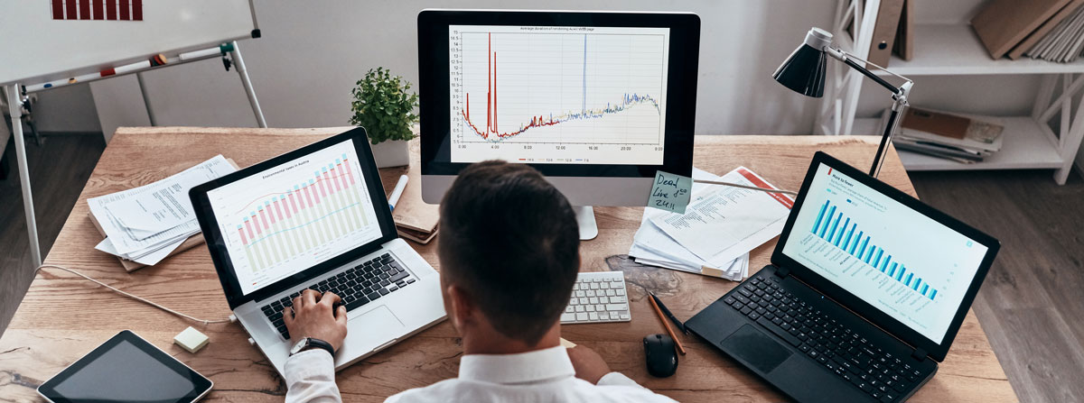 Analyzing sales. Top rear view of young businessman in formalwear analyzing data using computer while sitting in the office